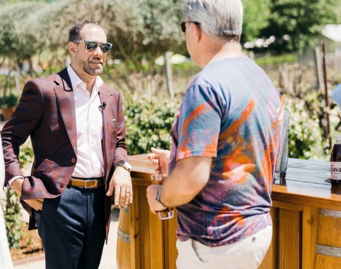 Man with colorful shirt having a discussion with man with plaid coat and shades