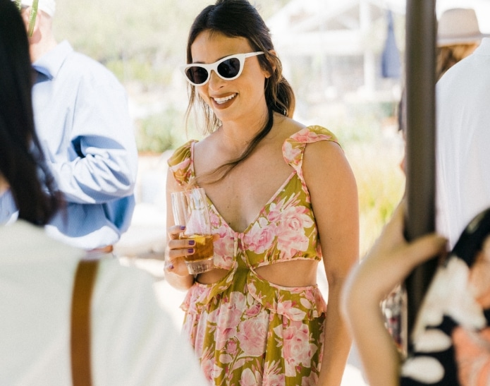 Woman with floral dress and shades having a drink while having a discussion